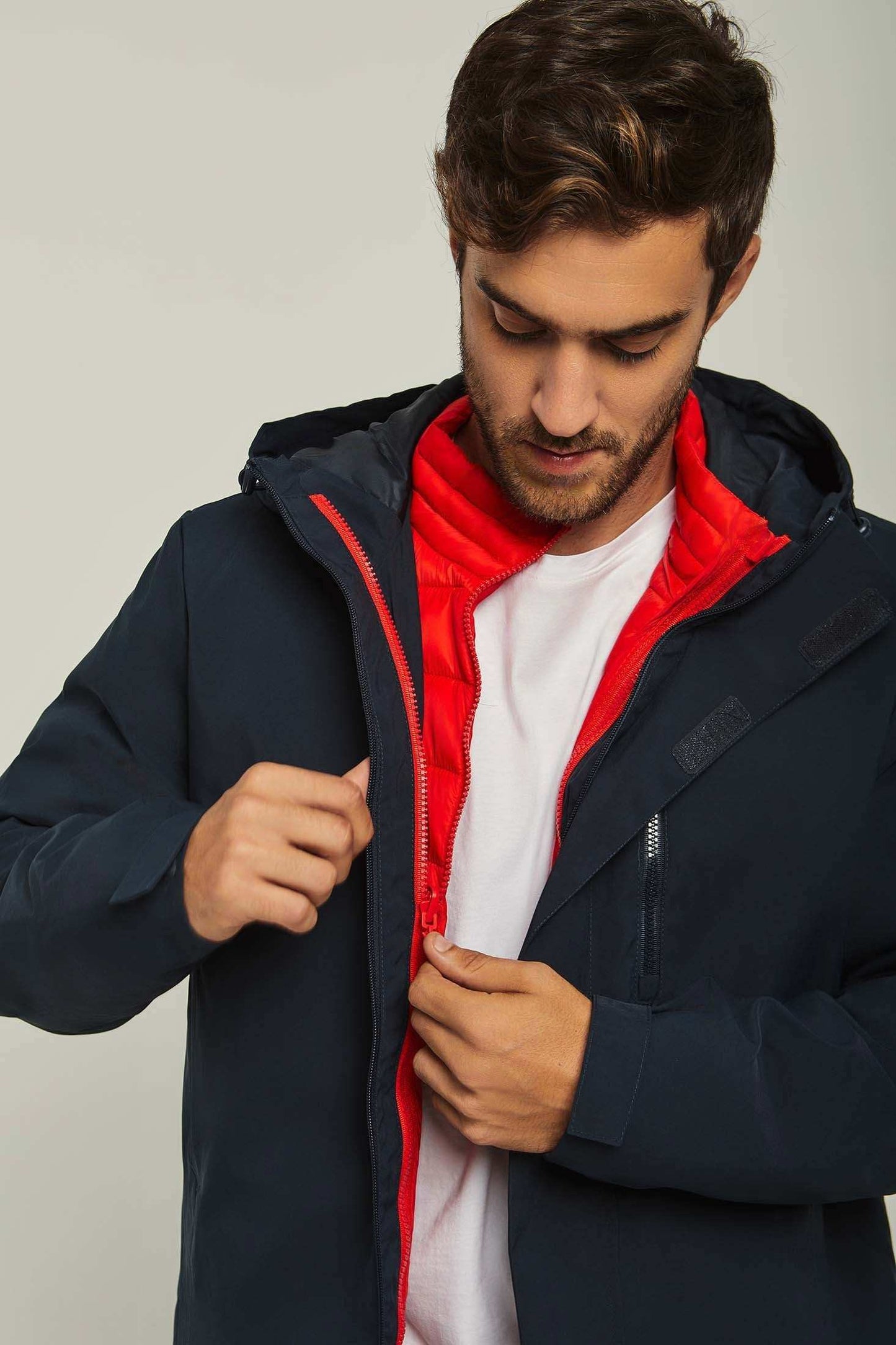 Man wearing a navy hooded jacket with red quilted inner lining and white t-shirt