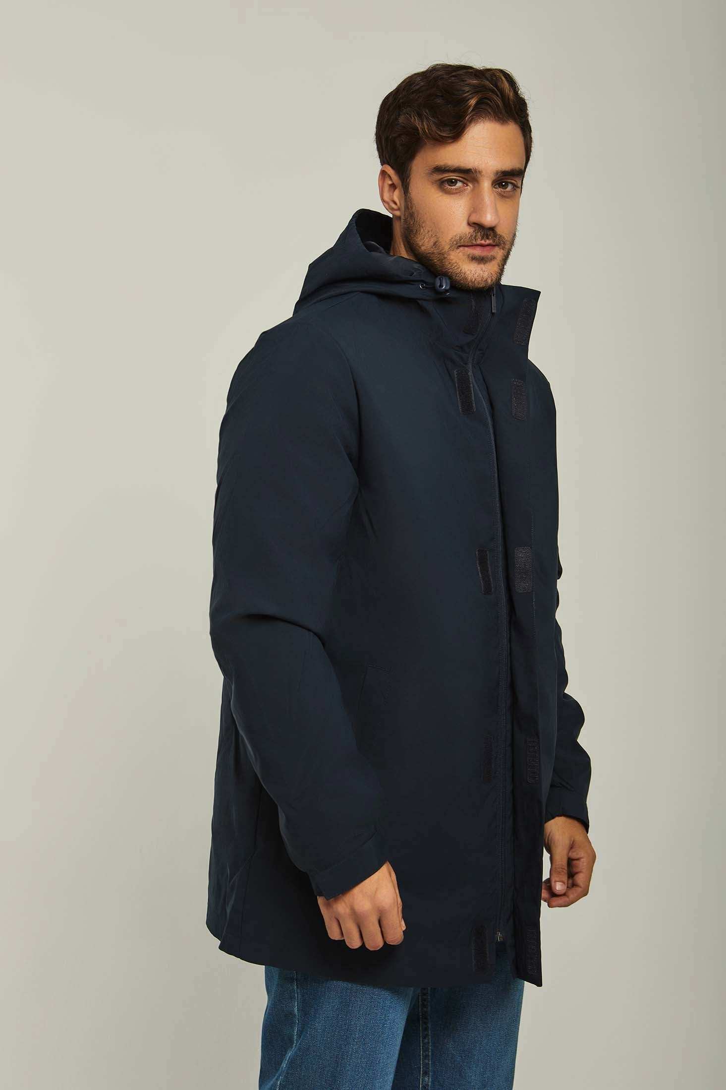 Man wearing a navy blue hooded winter jacket and blue jeans, casual fashion