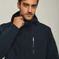 Man wearing a navy hooded jacket with chest zipper pocket, casual winter outerwear