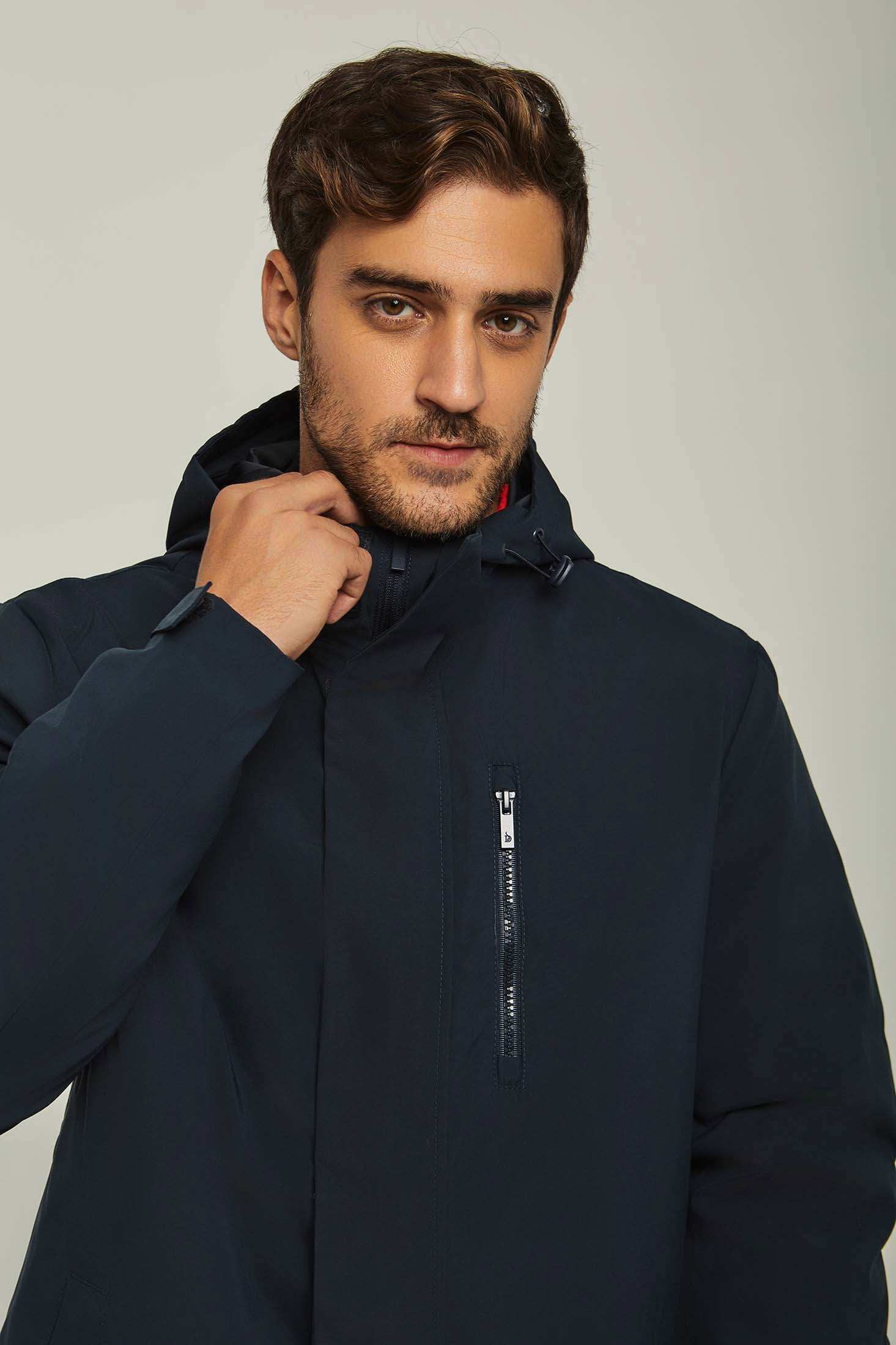 Man wearing a navy hooded jacket with chest zipper pocket, casual winter outerwear