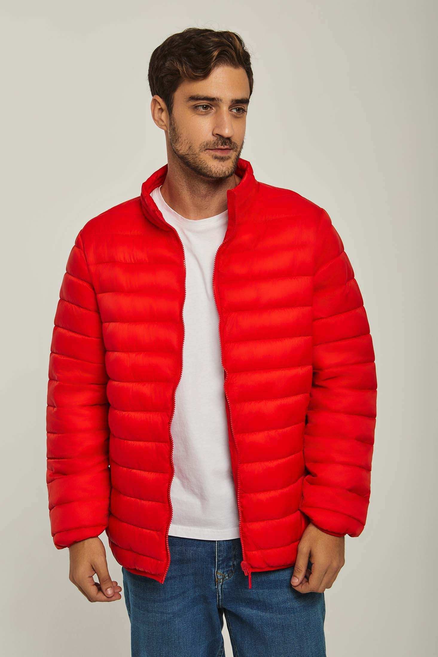 Man wearing a bright red puffer jacket over a white t-shirt and blue jeans