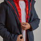 Man wearing a navy blue jacket with visible red quilted inner layer over white t-shirt