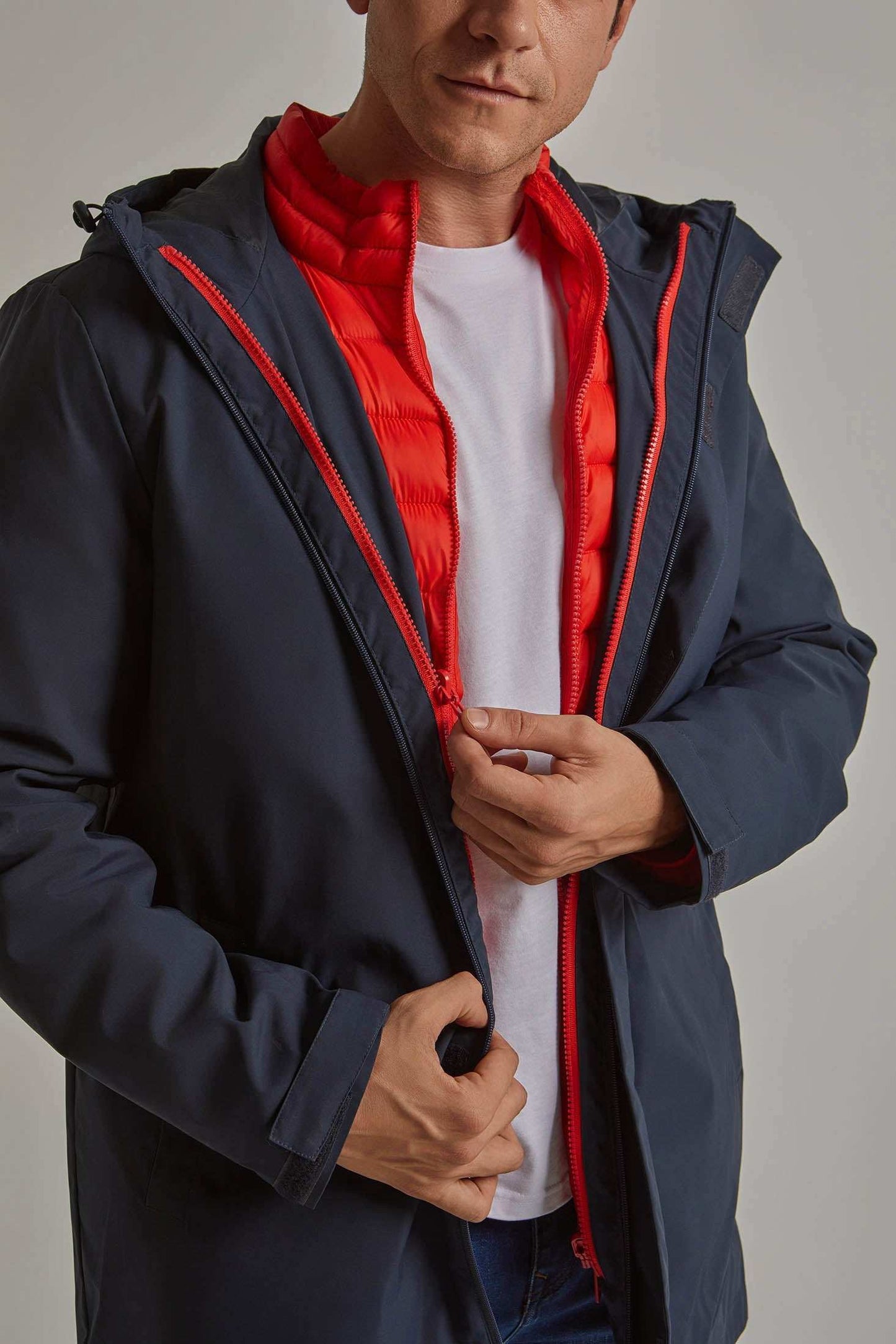 Man wearing a navy blue jacket with visible red quilted inner layer over white t-shirt