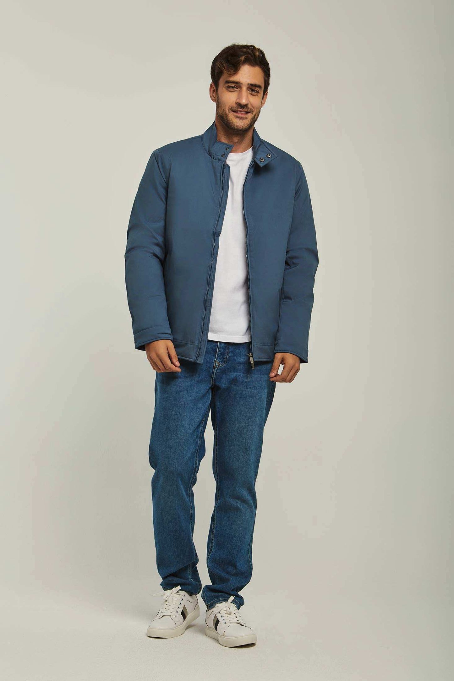 Man wearing blue casual jacket, white t-shirt, blue jeans, and white sneakers