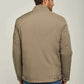 Man wearing beige casual jacket and blue jeans, back view on neutral background
