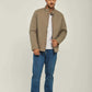 Man wearing a taupe casual jacket, white t-shirt, blue jeans, and white sneakers