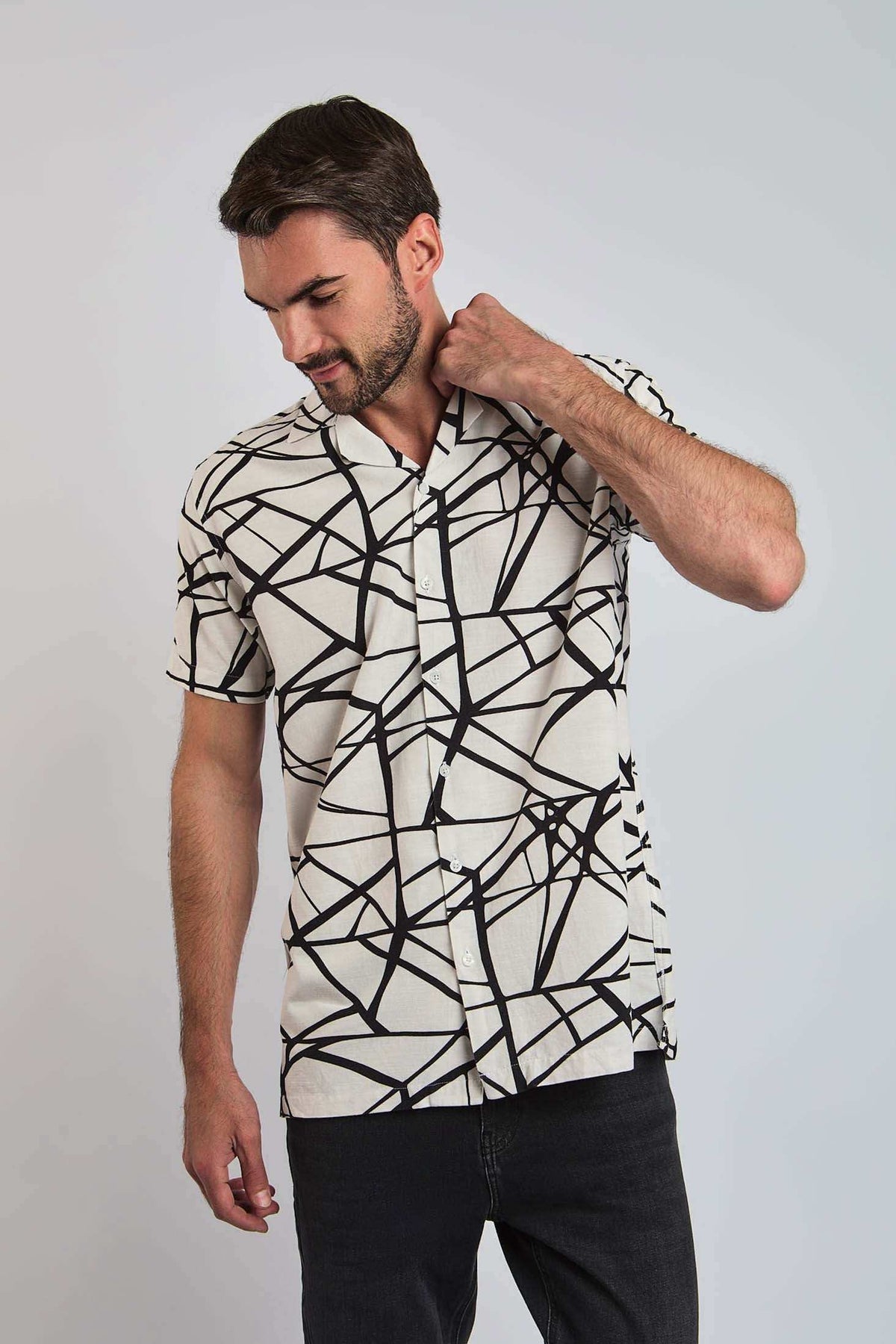 Man wearing a short sleeve white shirt with bold black geometric pattern, casual style