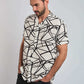 Man wearing short-sleeve black and white abstract print button-up shirt and dark jeans