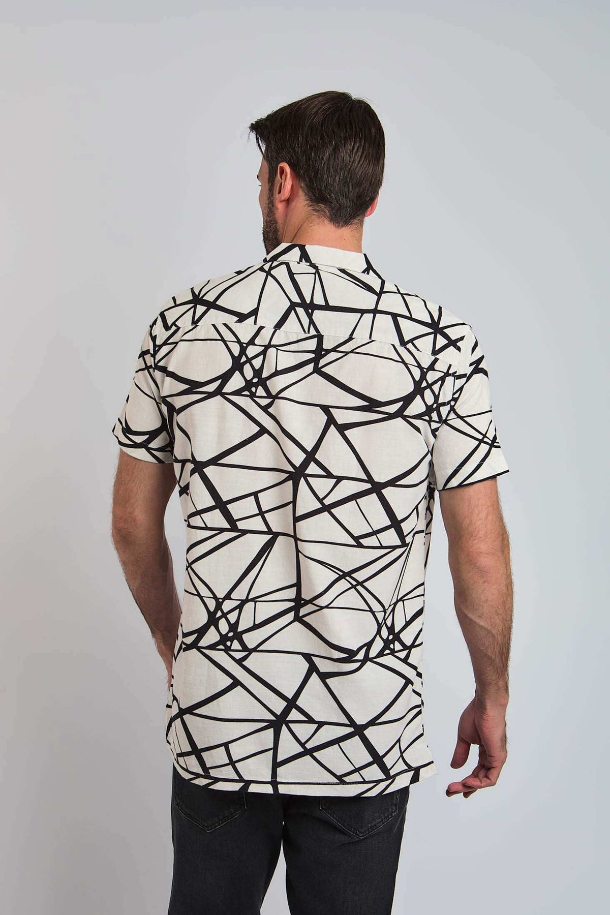 Man wearing short sleeve white shirt with bold black abstract lines, back view