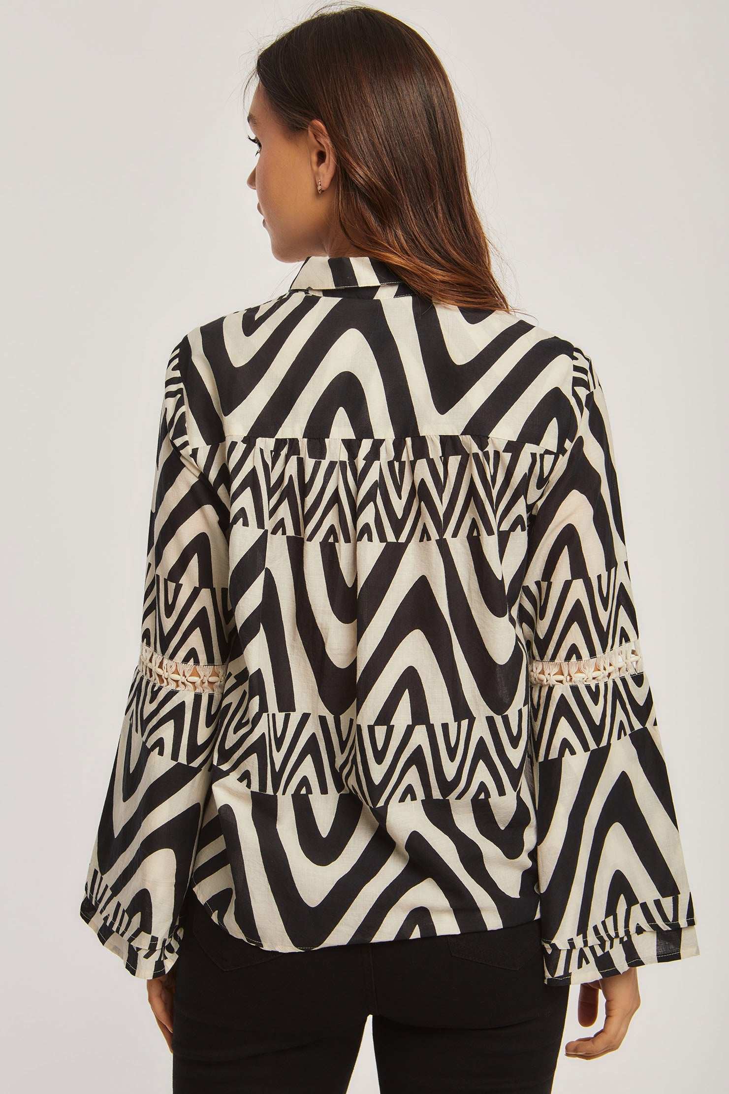 Woman wearing Dalydress black and white geometric print blouse, back view