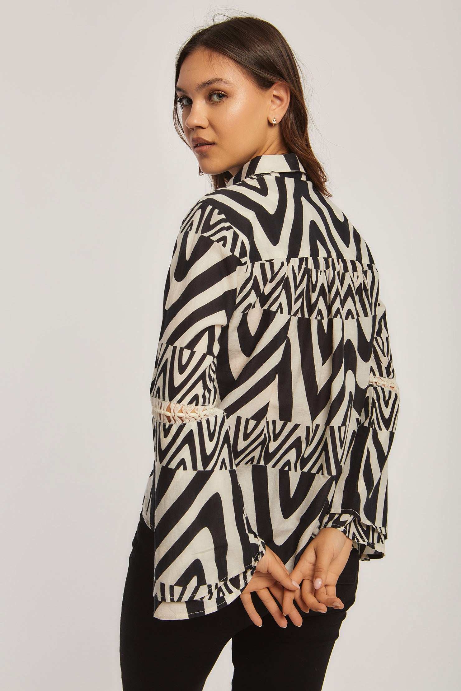 Woman wearing Dalydress black and white geometric patterned blouse, back view