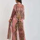 Woman wearing a long, sheer pink patterned kimono with wide sleeves and belted waist