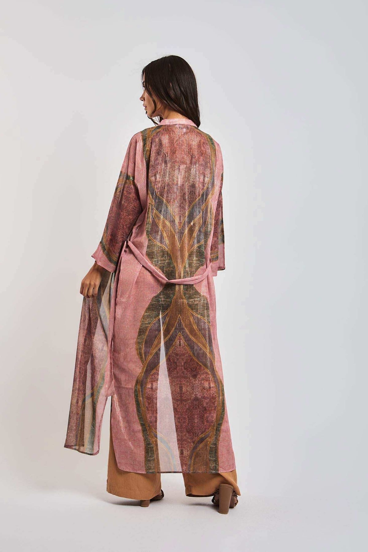 Woman wearing a long, sheer pink patterned kimono with wide sleeves and belted waist