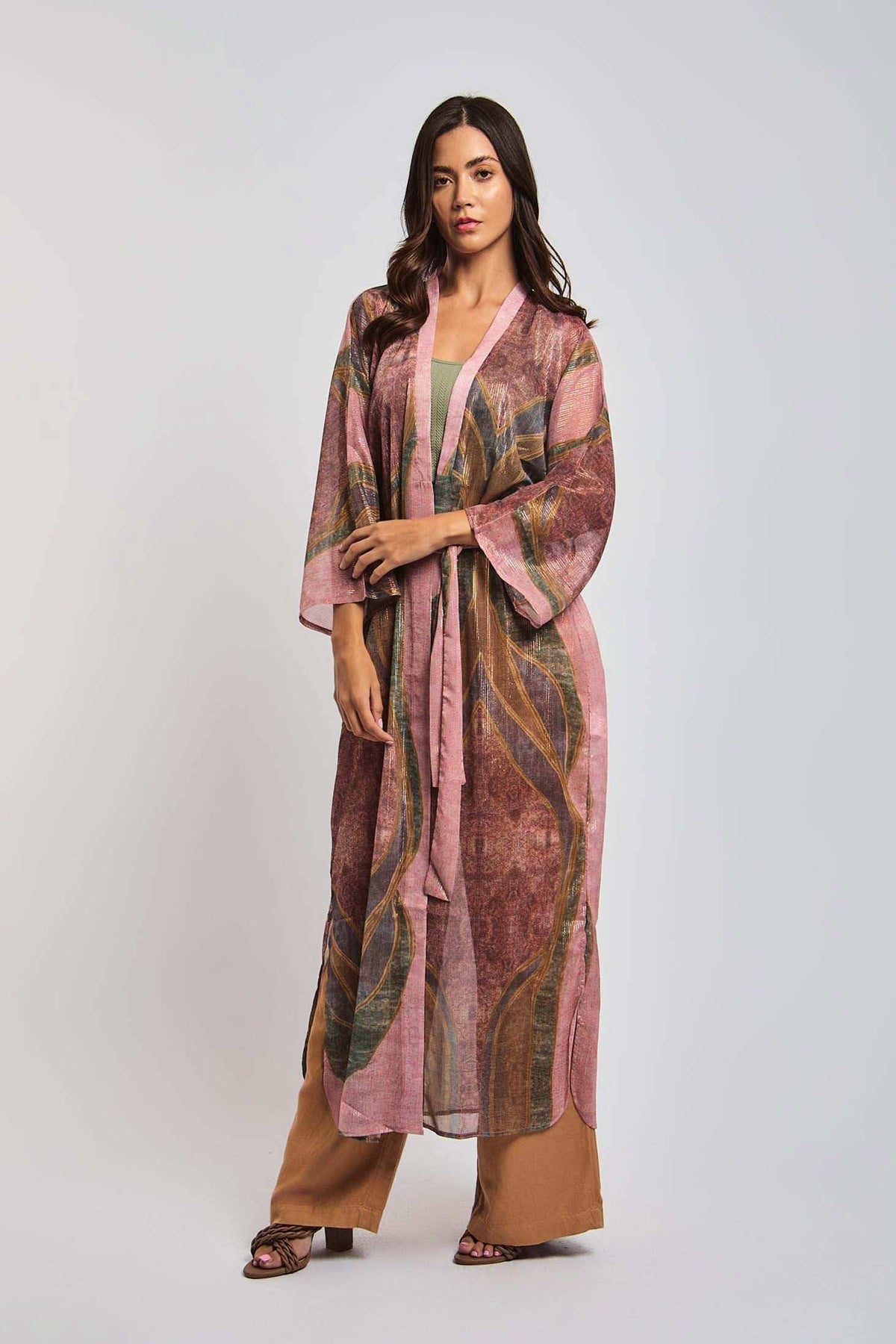 Woman wearing a long, sheer printed kimono over brown wide-leg pants, fashion photoshoot