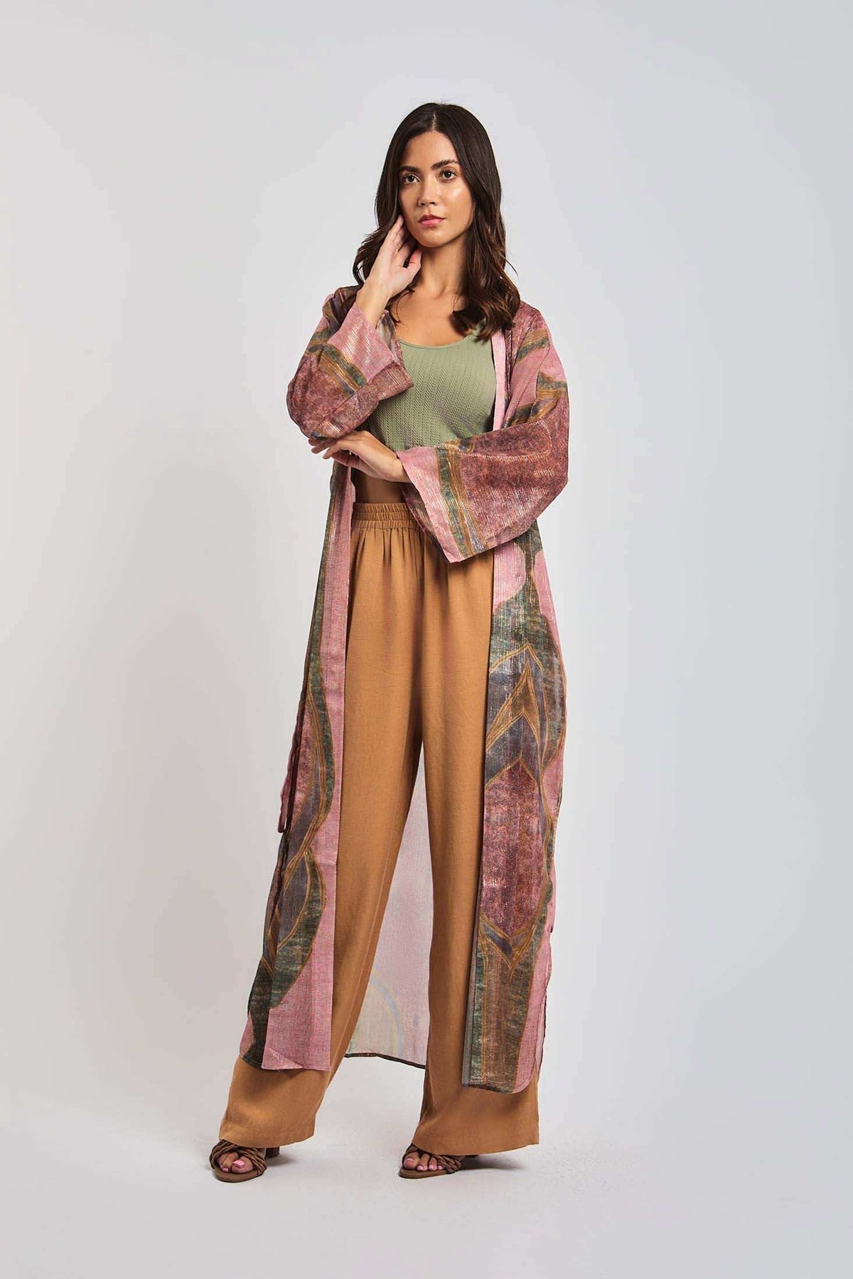 Woman wearing a green top, light brown pants, and a long patterned kimono jacket