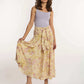 Woman in sleeveless lilac top and yellow floral maxi skirt from Dalydress standing on white background