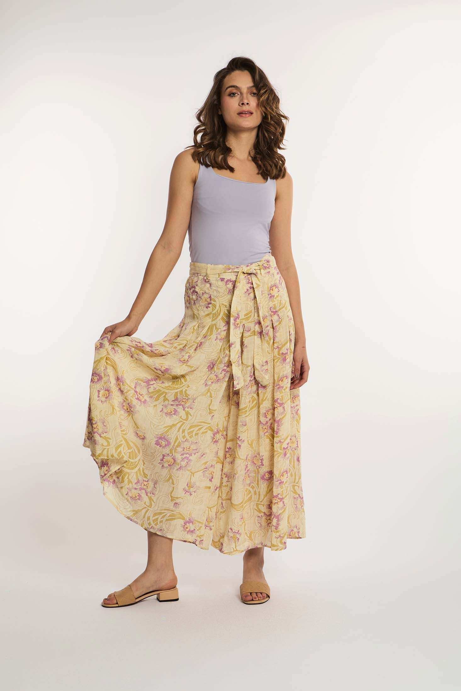 Woman in sleeveless lilac top and yellow floral maxi skirt from Dalydress standing on white background