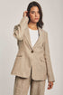 Woman wearing beige linen blazer and pants set from Dalydress against neutral background