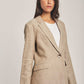 Woman wearing beige linen blazer and pants from Dalydress against plain background