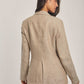 Woman wearing a beige linen blazer and trousers from Dalydress, back view against plain background