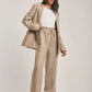 Woman wearing beige linen suit with tie-waist pants and white top, Dalydress collection