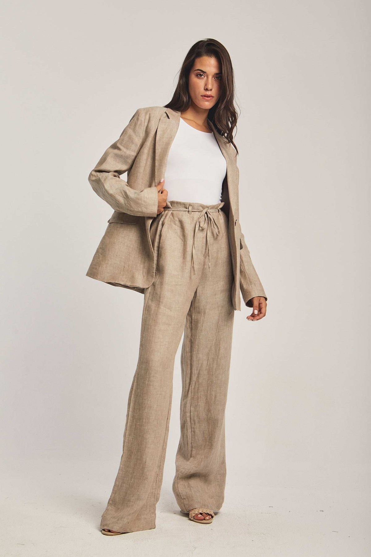 Woman wearing beige linen suit with tie-waist pants and white top, Dalydress collection