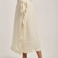 Woman wearing a cream striped midi skirt with tie waist from Dalydress, styled with sandals.