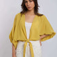 Woman wearing Dalydress yellow tie-front blouse and white studded pants