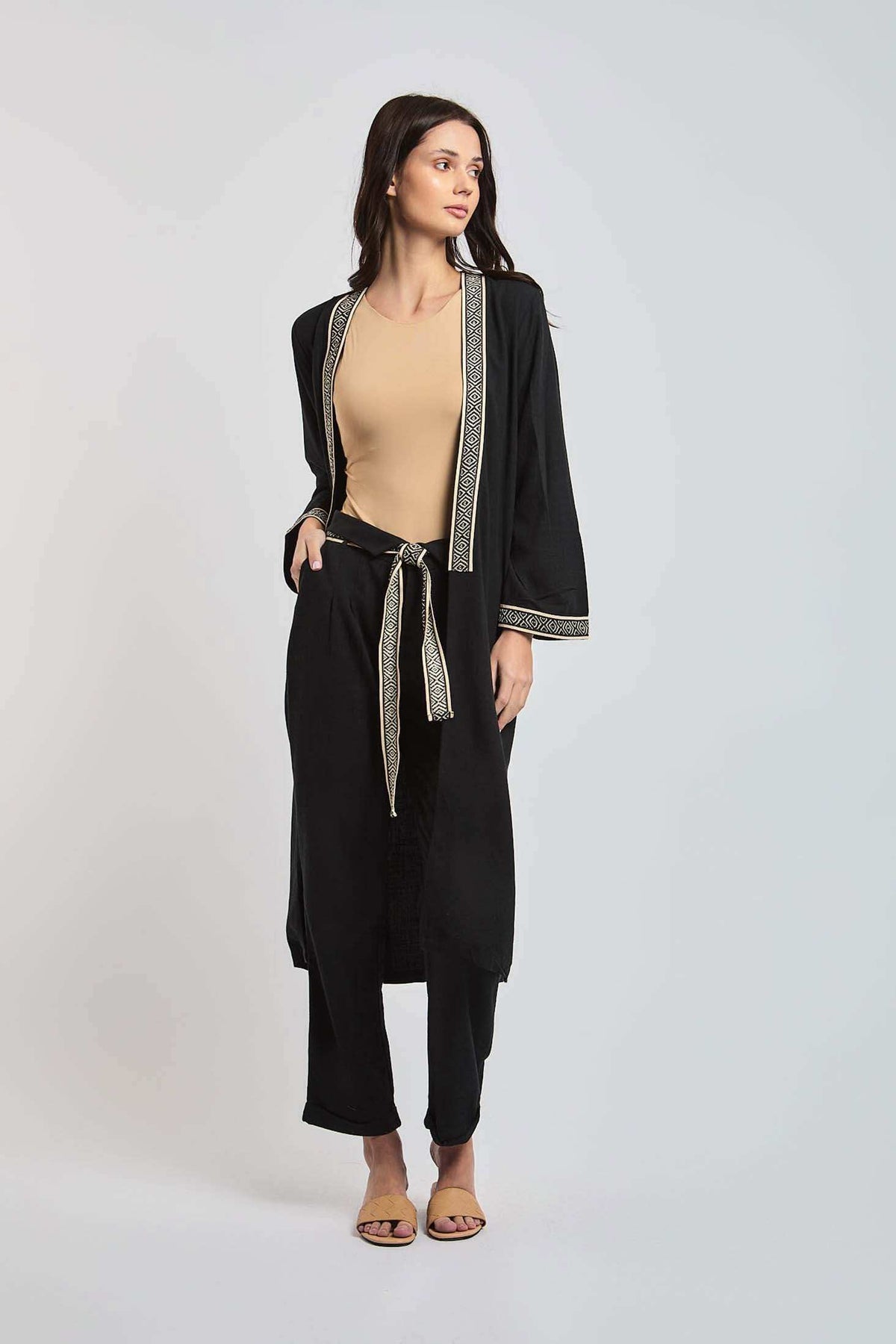 Woman wearing Dalydress black kimono set with geometric trim and beige top, standing in studio