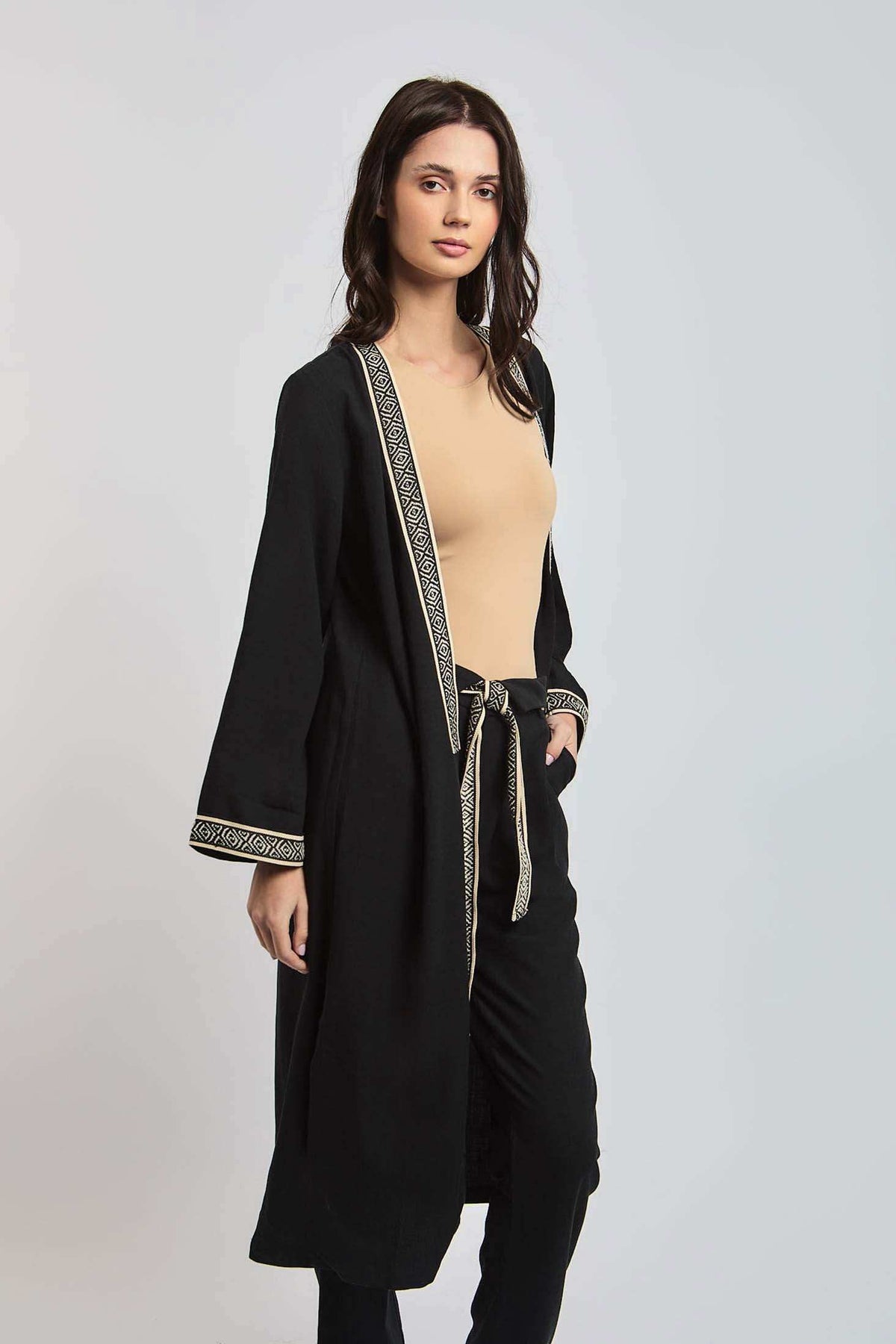 Woman modeling Dalydress black long cardigan with beige geometric trim, casual women's wear