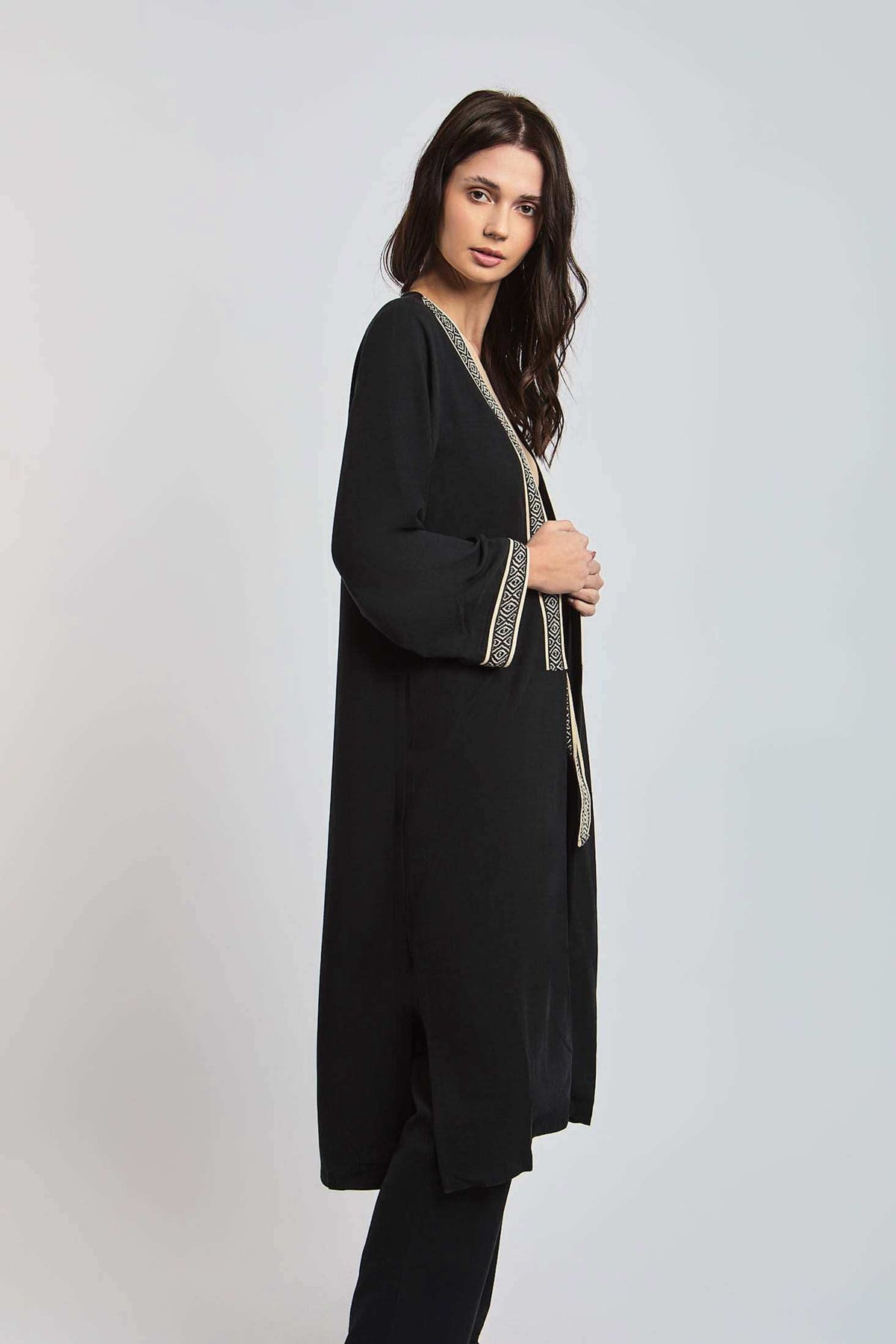 Woman wearing a Dalydress black long cardigan with geometric trim, modern Egyptian fashion