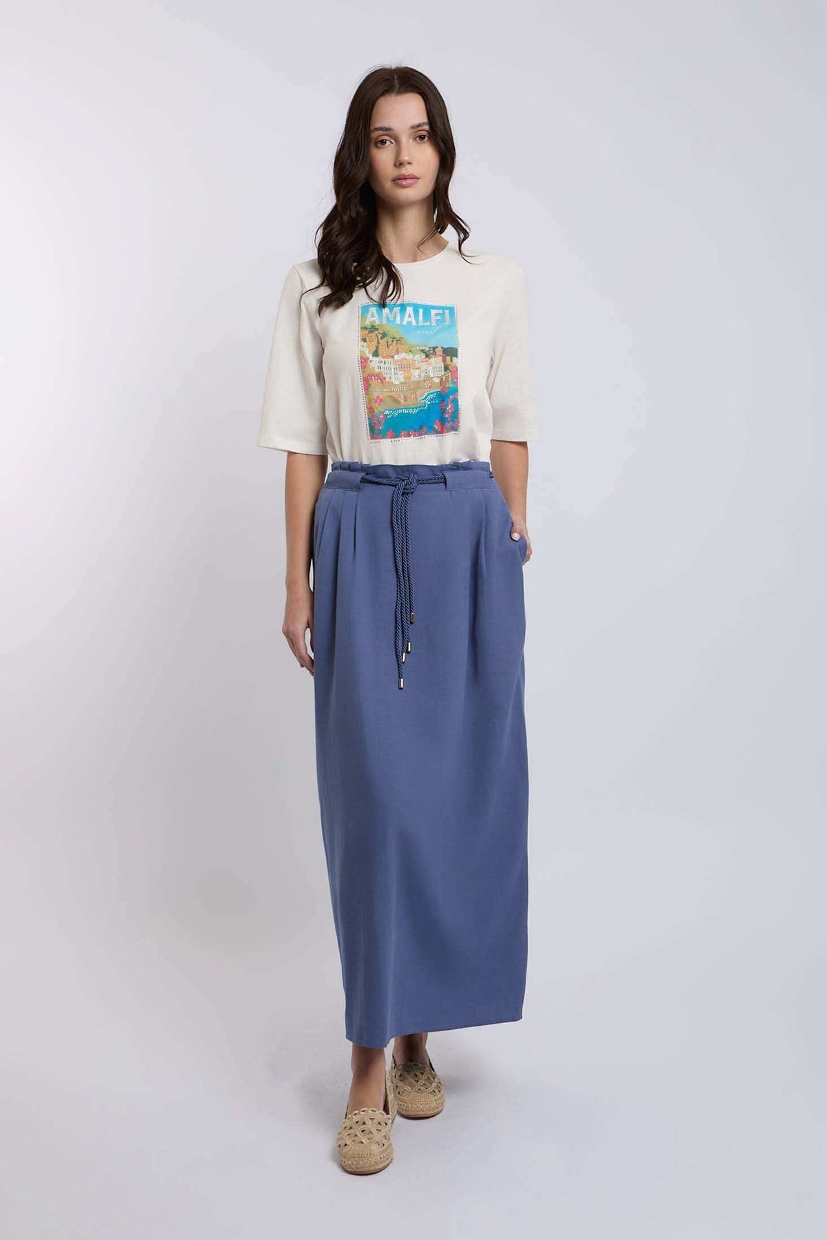 Woman wearing Dalydress casual Amalfi graphic t-shirt and blue maxi skirt, studio background