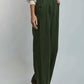 Woman wearing Dalydress olive green wide-leg pants and white blouse, side view