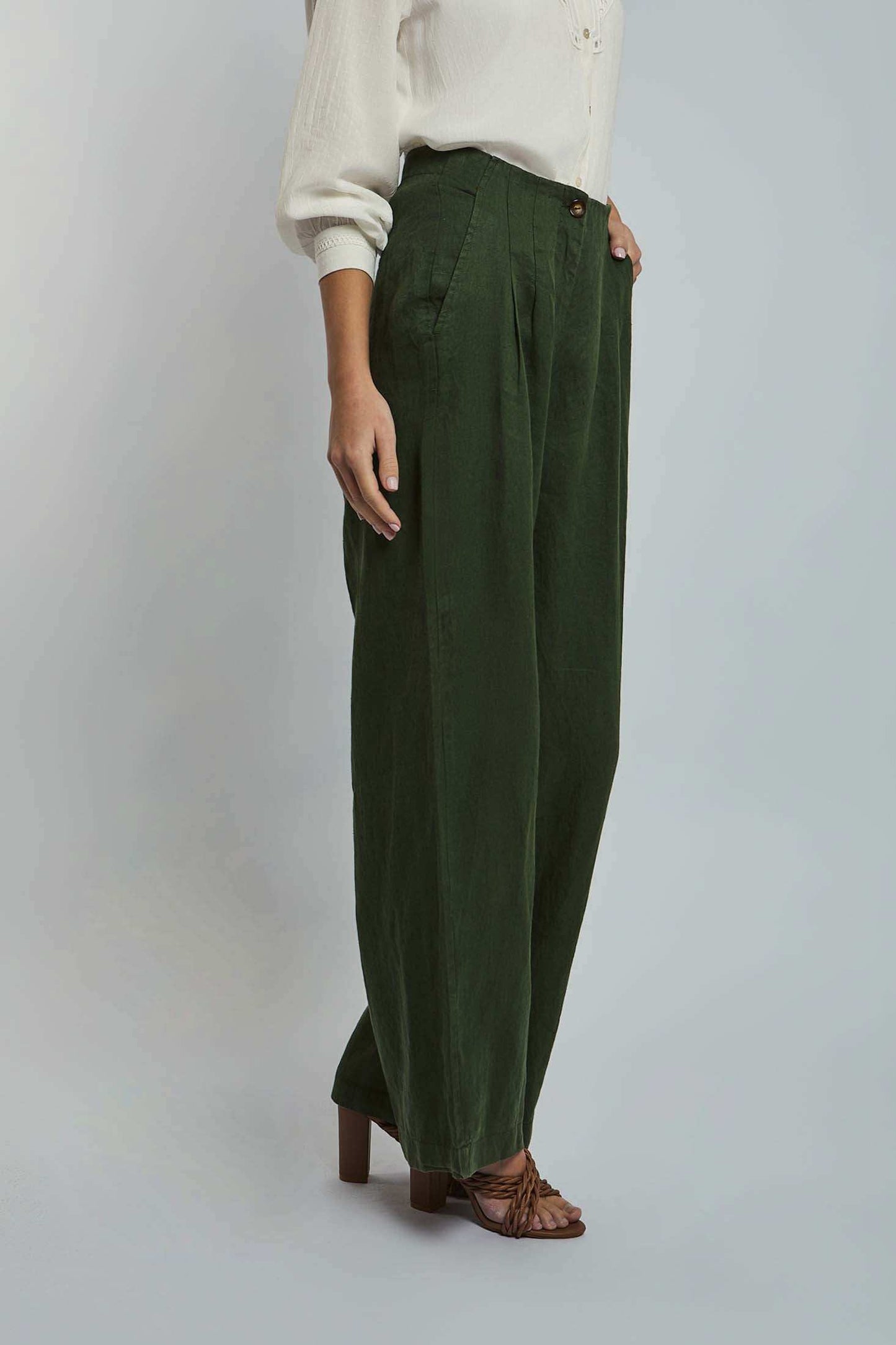 Woman wearing Dalydress olive green wide-leg pants and white blouse, side view