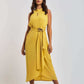 Woman in yellow sleeveless belted dress by Dalydress, standing against white background