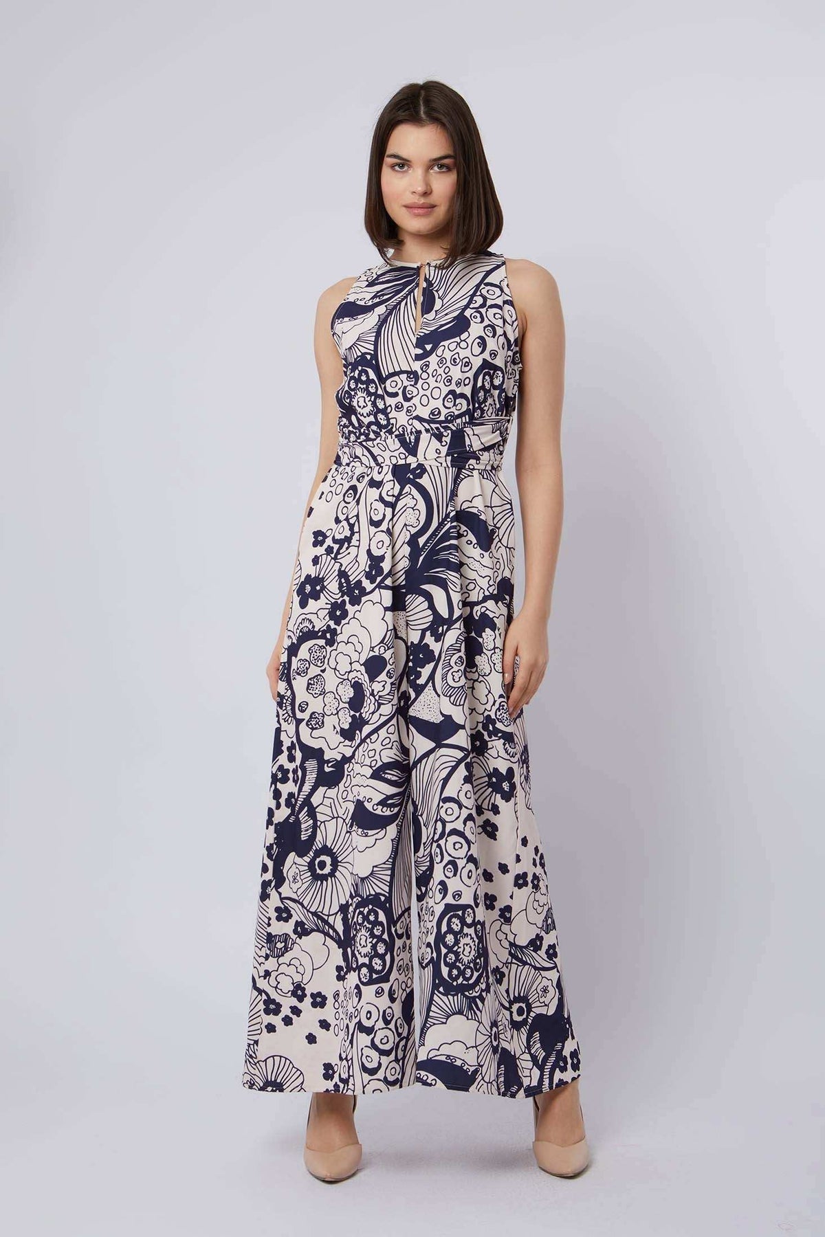 Woman in Dalydress sleeveless navy floral maxi dress, standing against light background