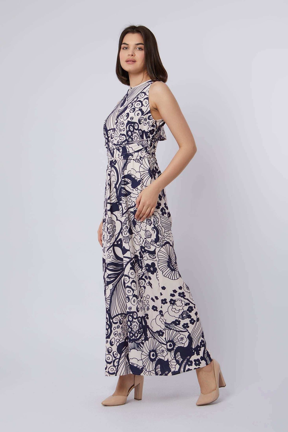 Woman modeling Dalydress sleeveless navy and white floral maxi dress, neutral heels, studio background