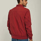Man wearing a casual red jacket and blue jeans, back view, neutral background