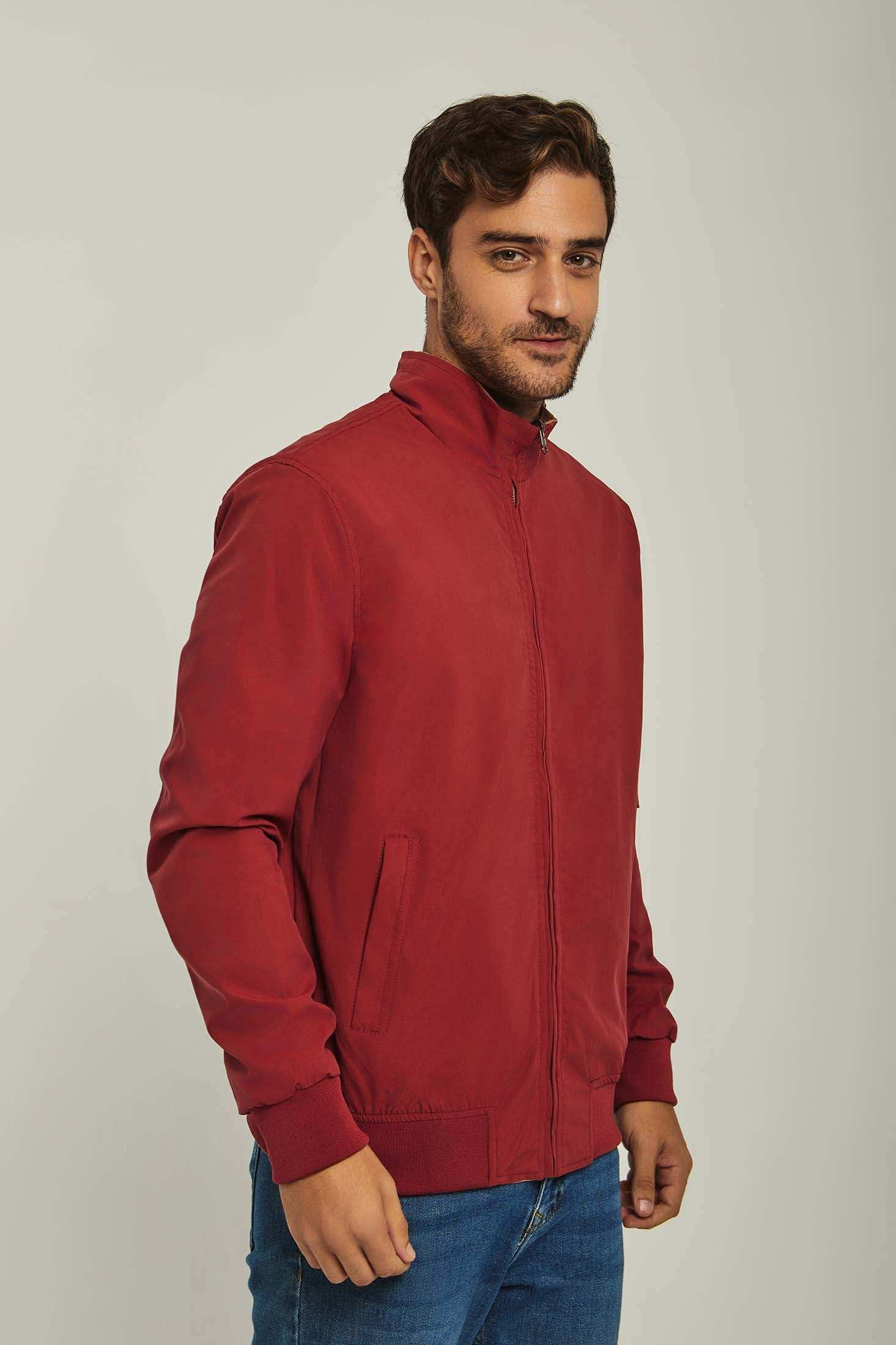 Man wearing a casual red zip-up jacket with side pockets and blue jeans