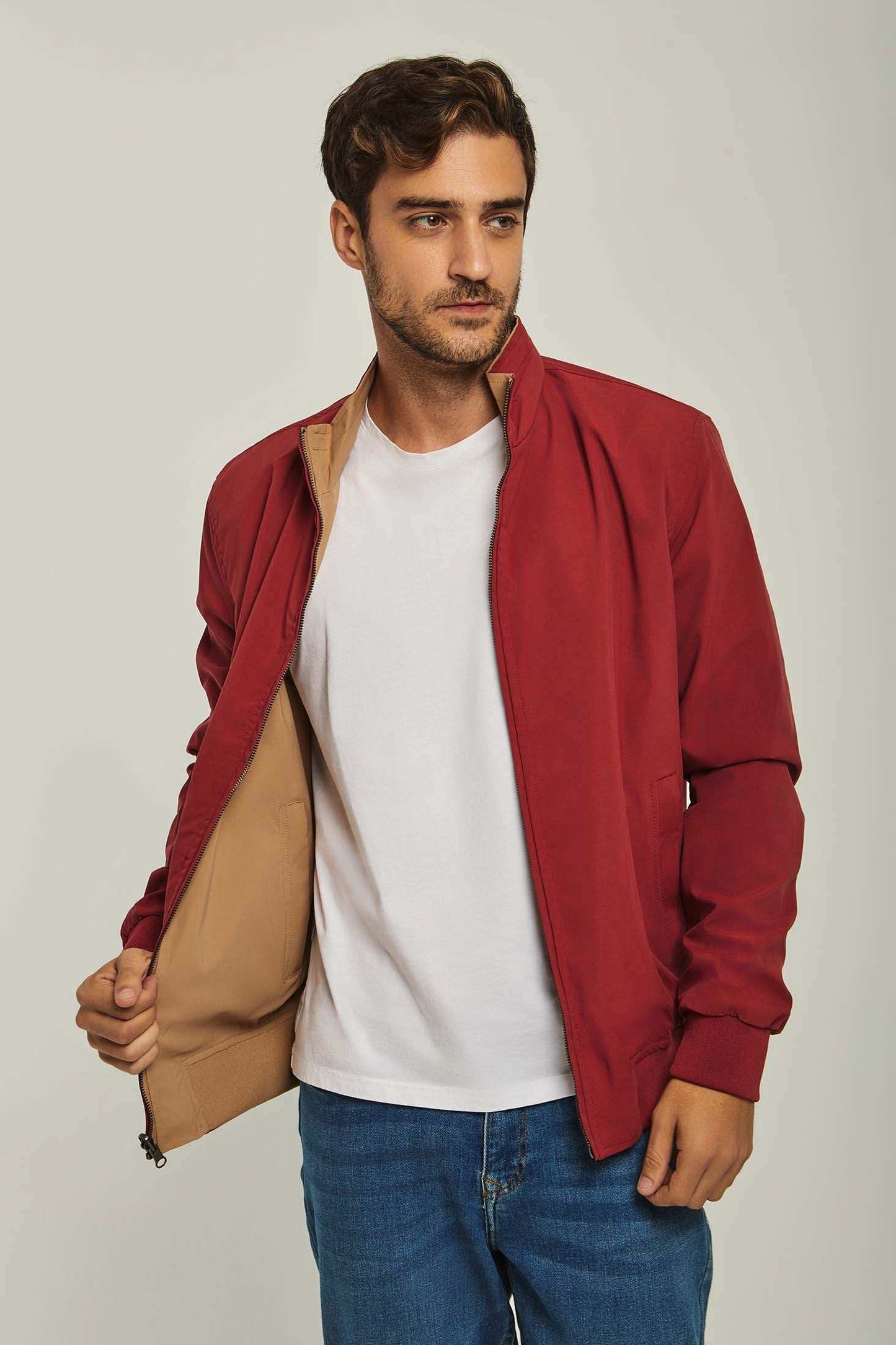 Man modeling casual red jacket with beige lining, white t-shirt, and blue jeans