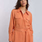 Woman wearing an orange belted long-sleeve Dalydress shirt with chest pockets.