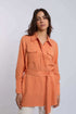 Woman wearing an orange belted long-sleeve Dalydress shirt with chest pockets.
