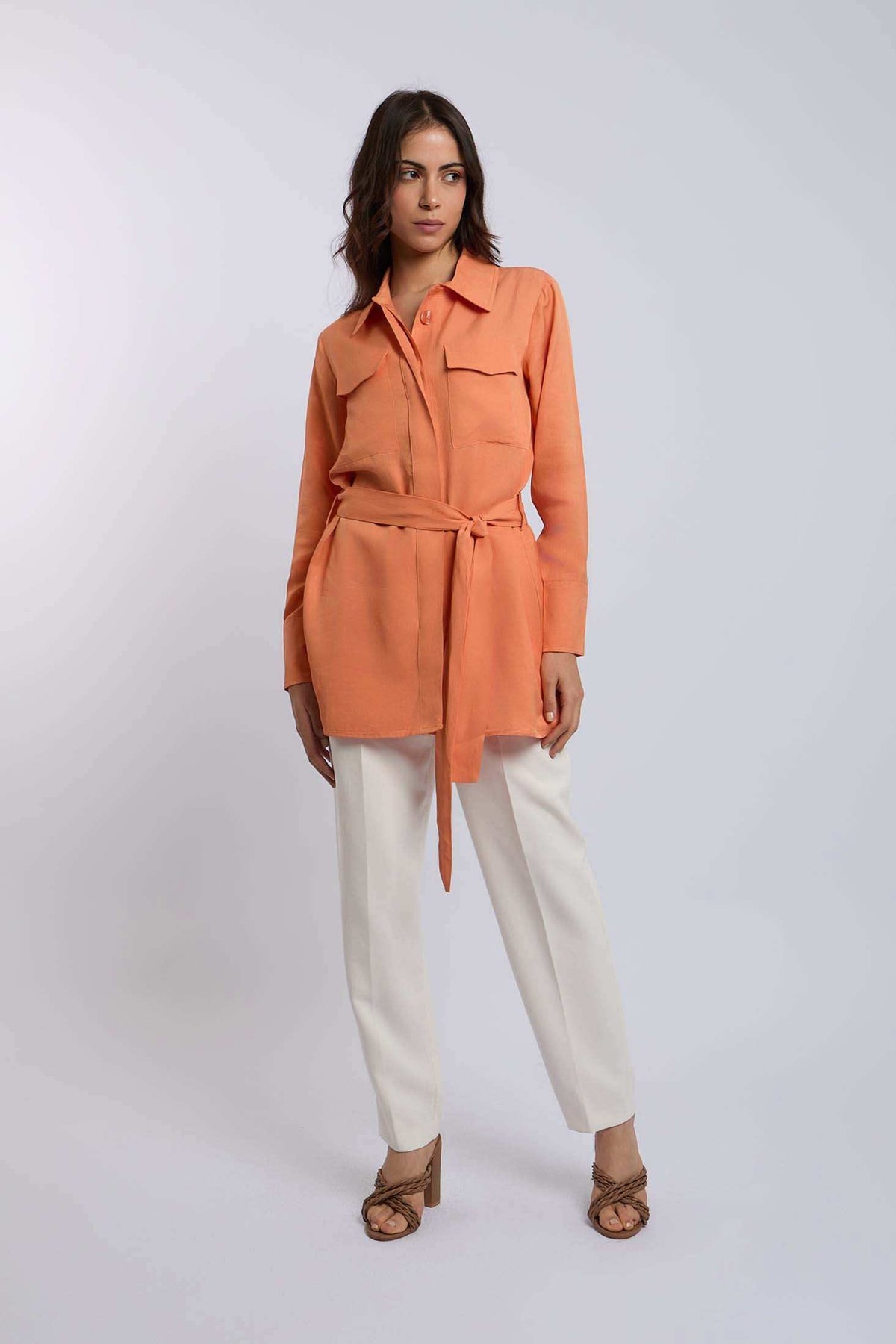 Woman wearing a peach belted shirt and white pants from Dalydress, modern casual style