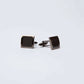 Pair of black square cufflinks with textured pattern on white background