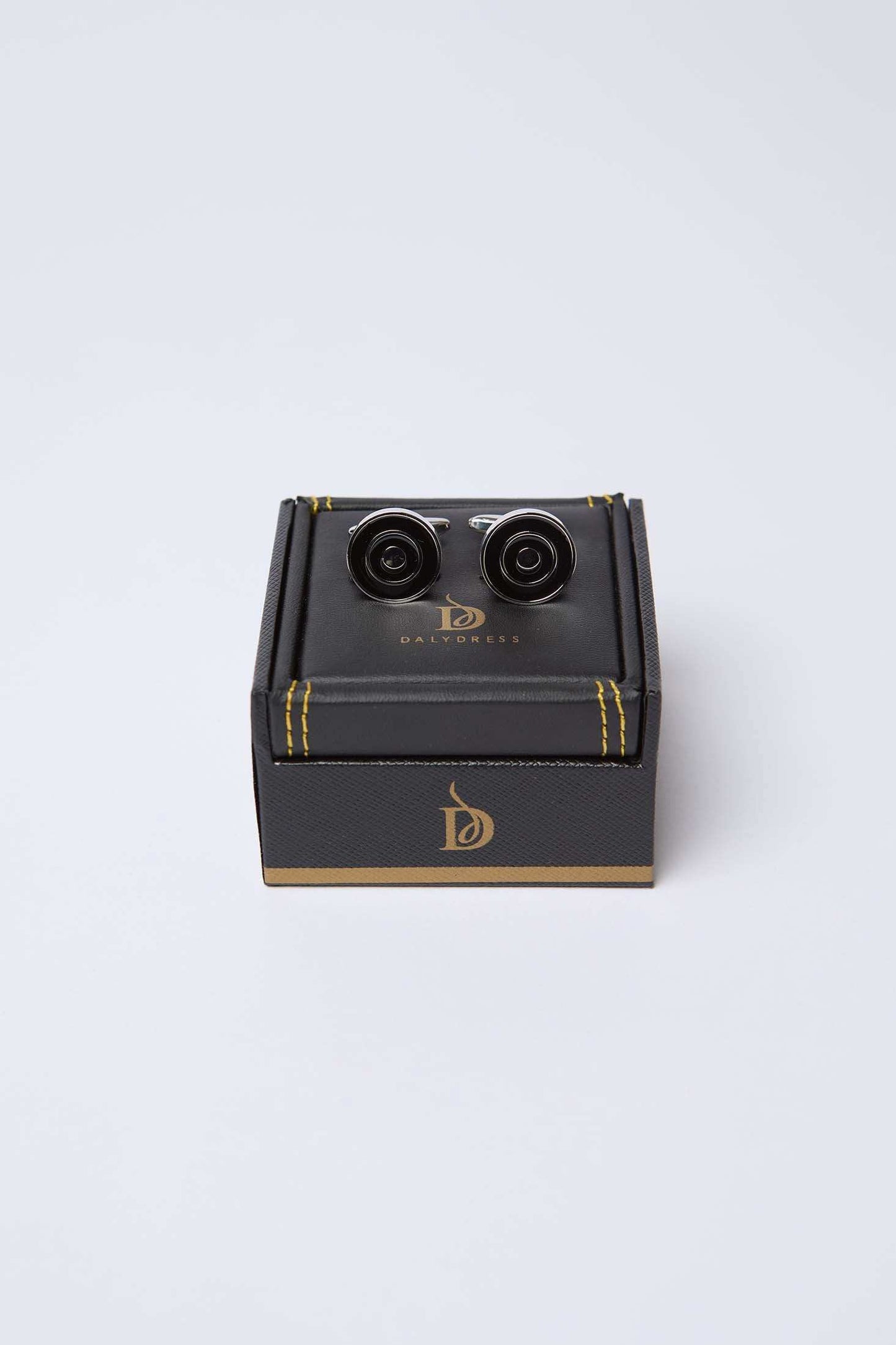 Black and silver round cufflinks on a dark gift box with gold accents, men's accessories