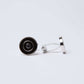 Silver and black round cufflinks with concentric circles on white background