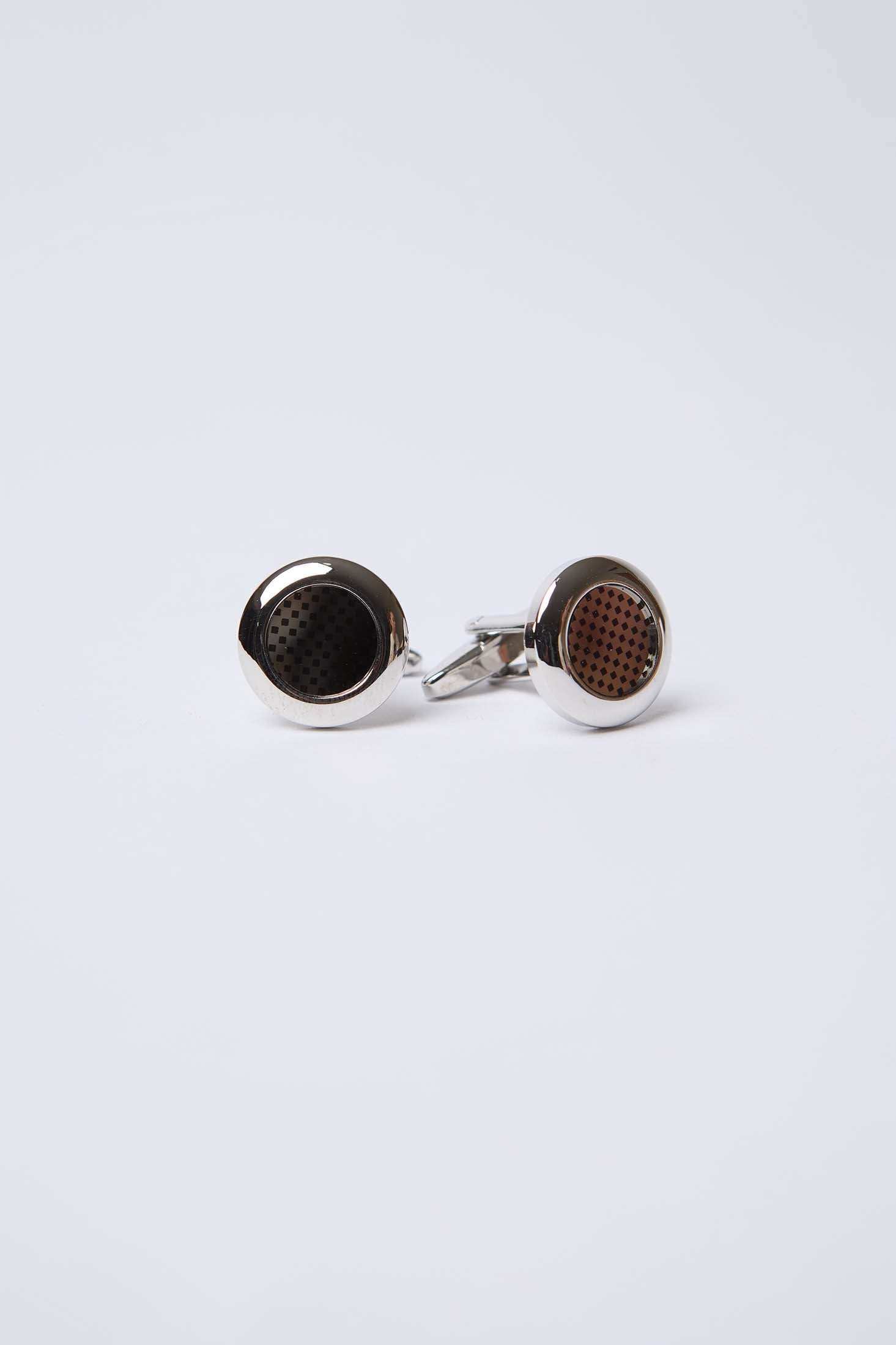 Round silver cufflinks with black and brown patterned inlays on white background