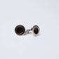 Pair of round silver cufflinks with black centers on a plain white background