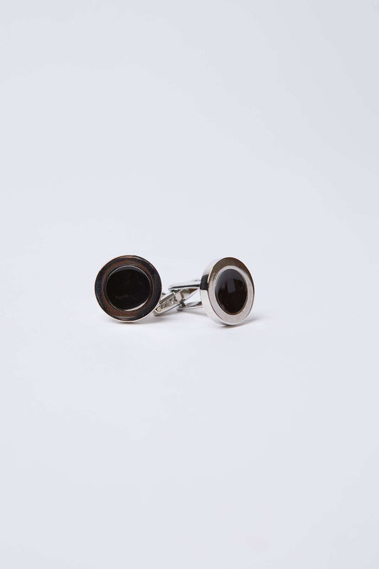 Pair of round silver cufflinks with black centers on a plain white background