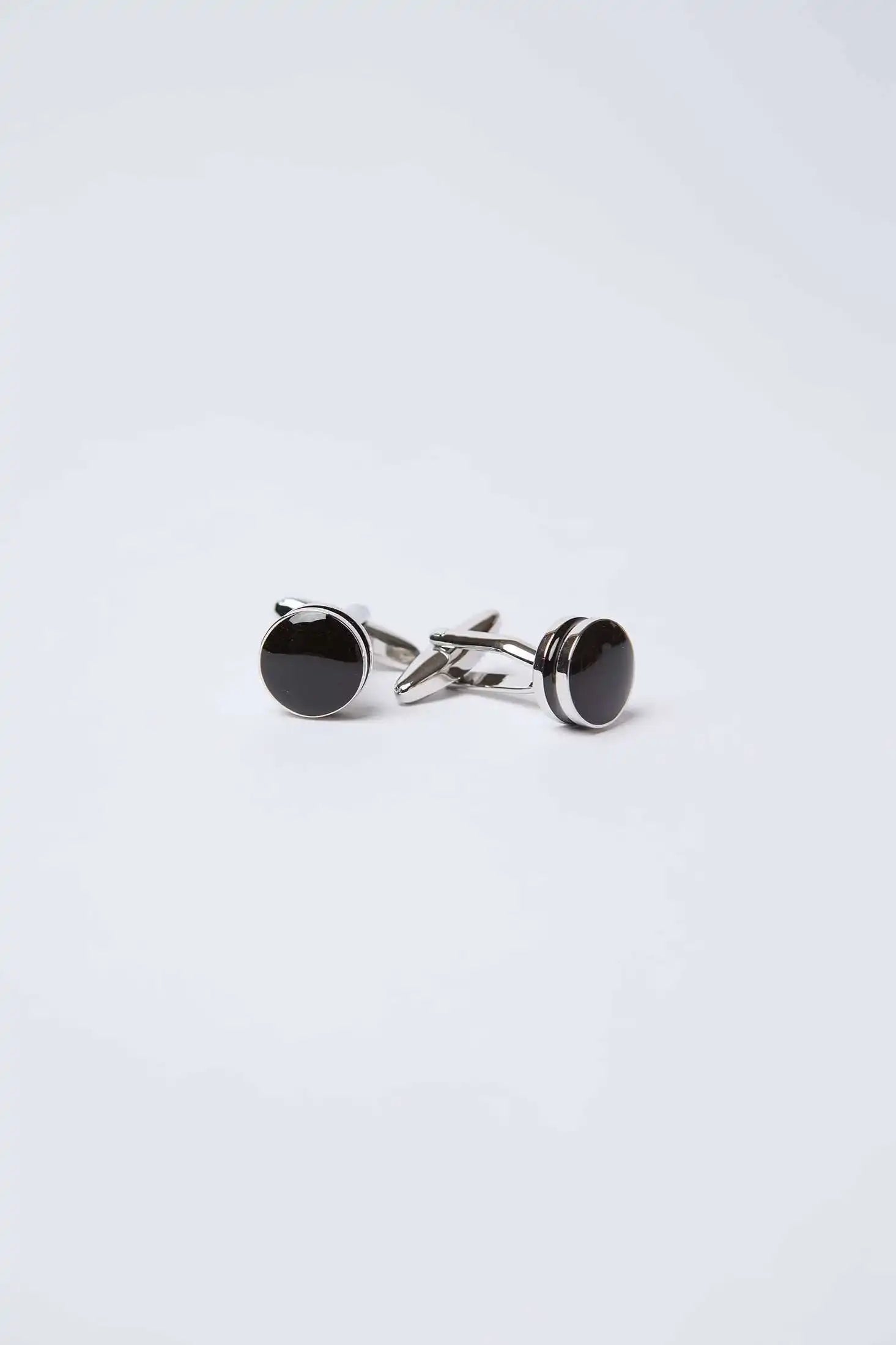 Pair of round black and silver cufflinks on a plain white background